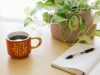 black retractable pen on opened book beside red and white go get'em-printed coffee cup