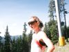Woman pauses near a ski lift on a sunny day.