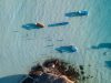 Boats float in beautiful, clear blue water.