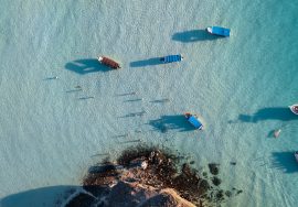 Boats float in beautiful, clear blue water.
